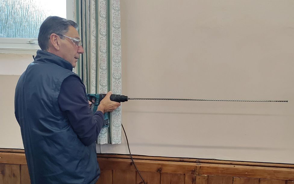 One of the installers with a very long masonry drill.